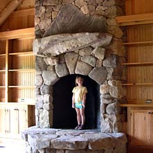 Arched opening fieldstone fireplace with keystone, natural stone mantel with unique mountain shaped stone backing